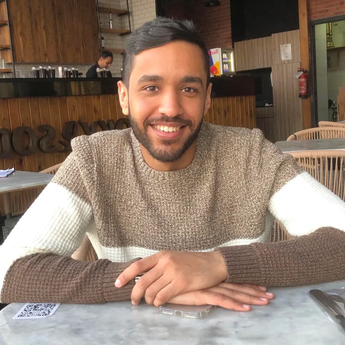 Marwan Elsayed smiling, seated at a table in a café